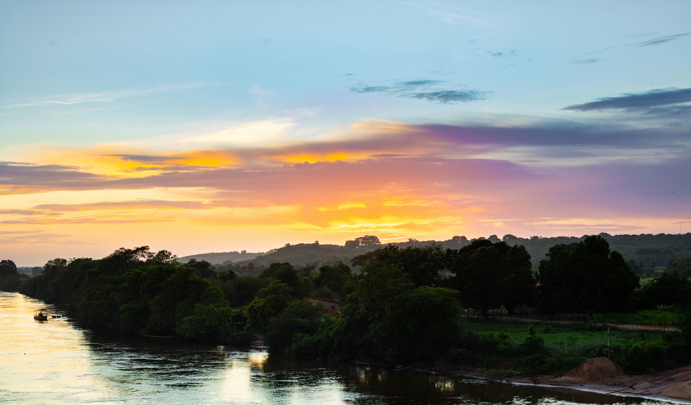 Image of the sun setting on a river bank